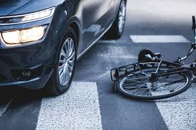 bicycle laying flat on a crosswalk beside a car